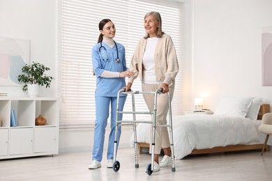 Nurse helping senior woman with walking frame in clinic