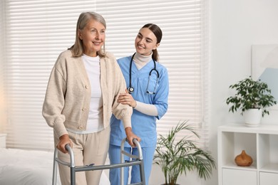 Photo of Nurse helping senior woman with walking frame in clinic