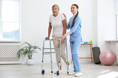 Nurse helping senior woman with walking frame in clinic