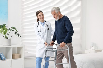 Doctor helping senior man with walking frame in clinic