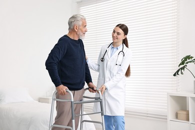 Doctor helping senior man with walking frame in clinic