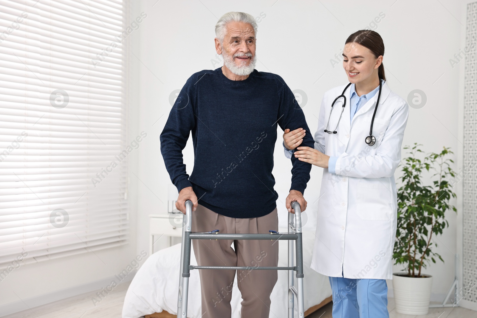 Photo of Doctor helping senior man with walking frame in clinic