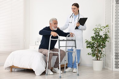 Photo of Doctor helping senior man with walking frame in clinic