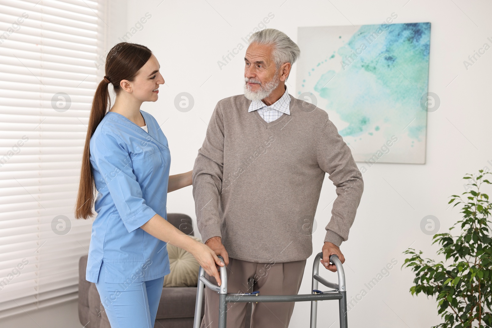 Photo of Nurse helping senior man with walking frame in clinic