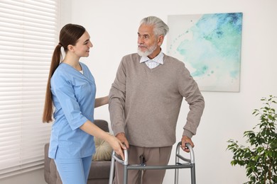 Photo of Nurse helping senior man with walking frame in clinic