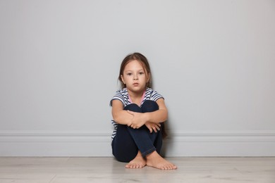 Photo of Orphanage concept. Sad girl sitting on floor indoors