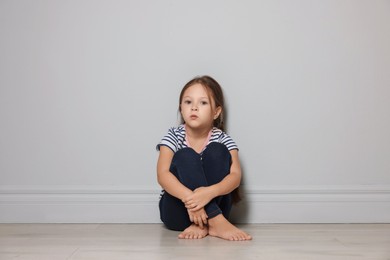 Photo of Orphanage concept. Sad girl sitting on floor indoors