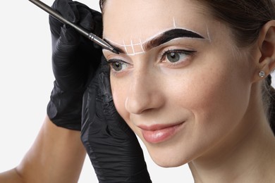 Young woman undergoing henna eyebrows dyeing procedure on light background, closeup