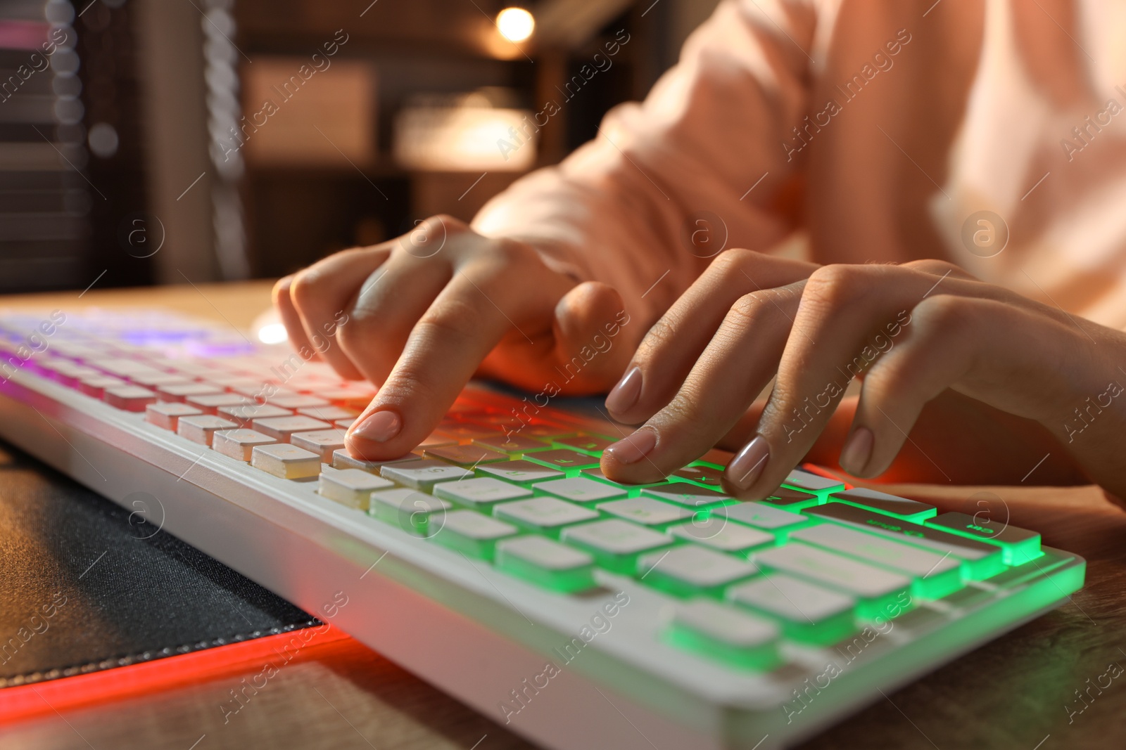 Photo of Girl using computer keyboard at wooden table indoors, closeup