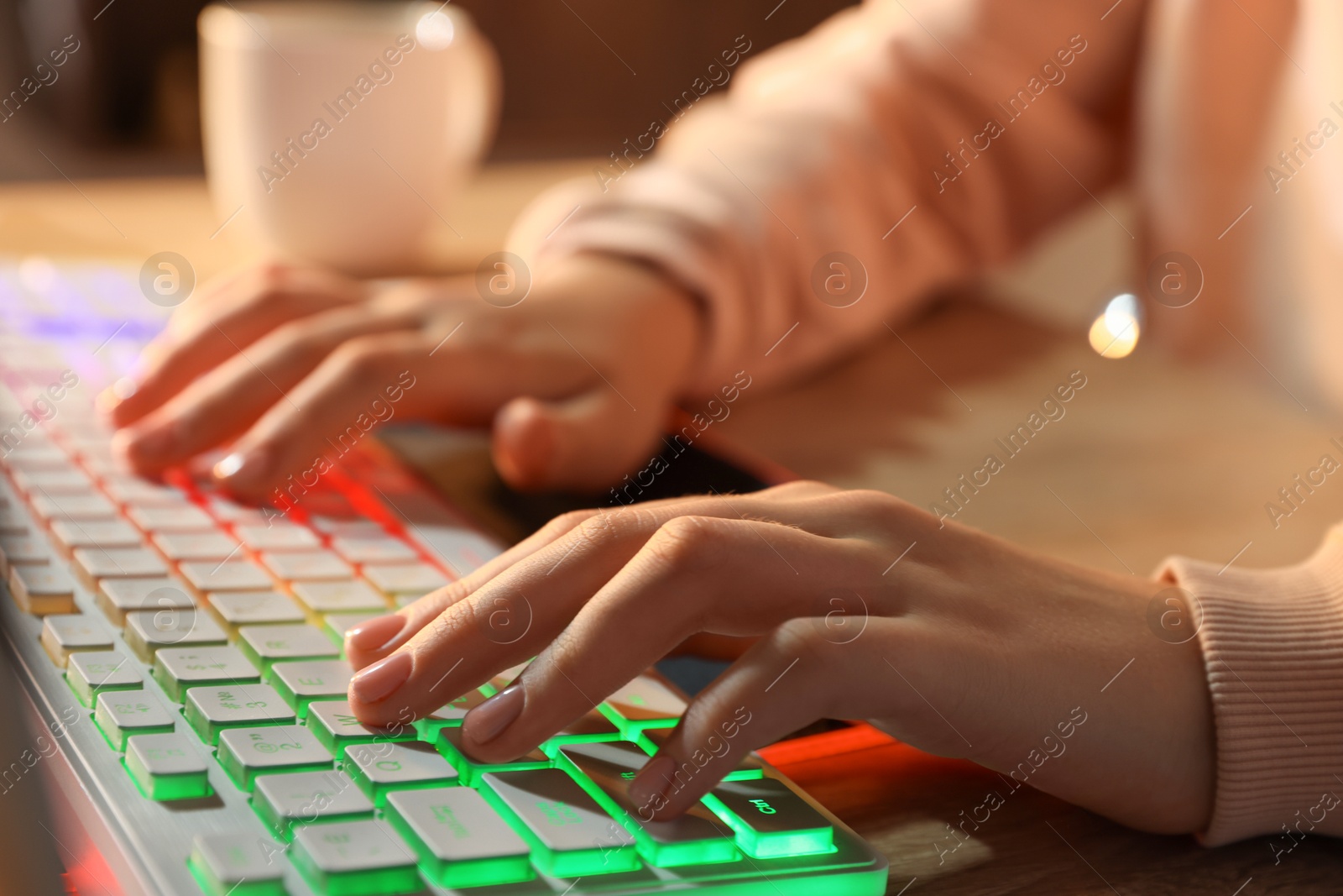 Photo of Girl using computer keyboard at table indoors, closeup