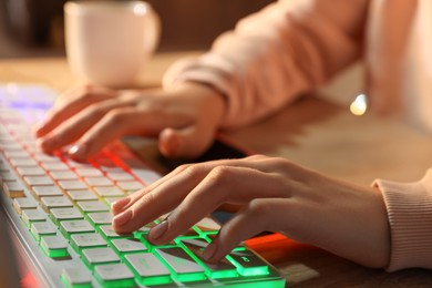 Photo of Girl using computer keyboard at table indoors, closeup