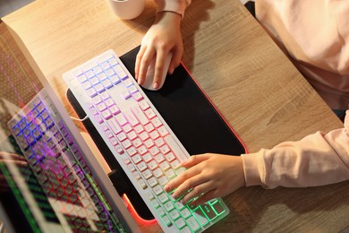 Photo of Girl using computer keyboard and mouse at wooden table indoors, above view