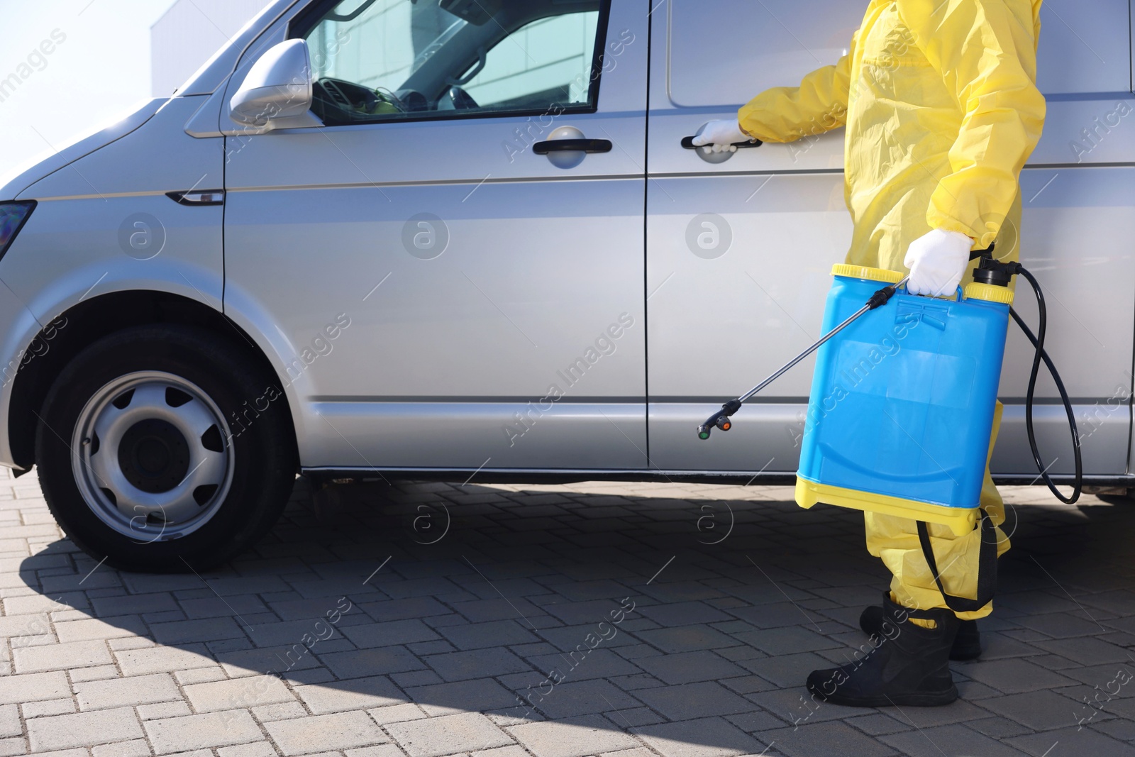 Photo of Pest control worker with spray tank near gray minibus outdoors, closeup