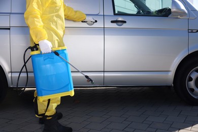 Pest control worker with spray tank near gray minibus outdoors, closeup