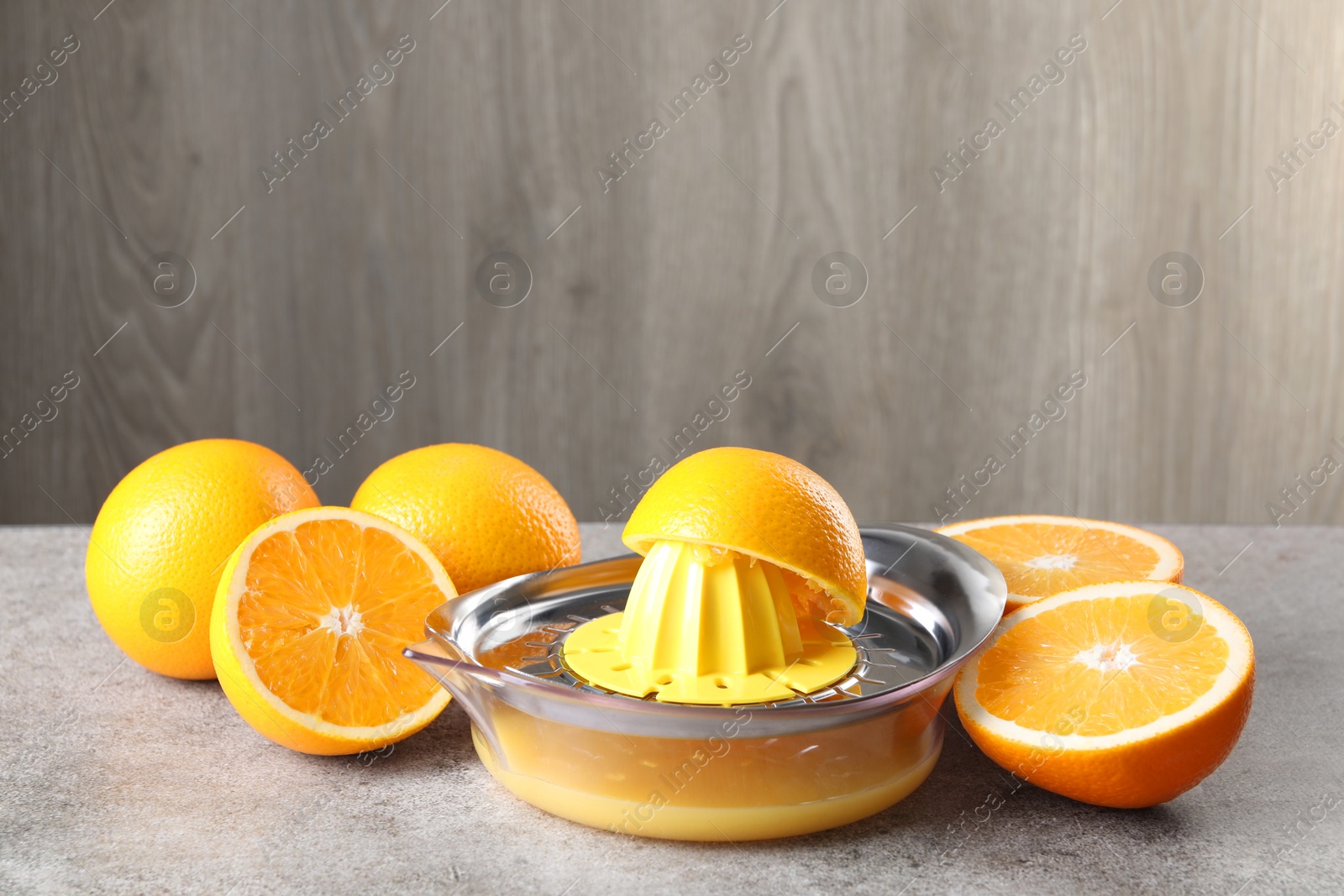 Photo of Metal juicer and oranges on grey table