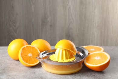 Photo of Metal juicer and oranges on grey table