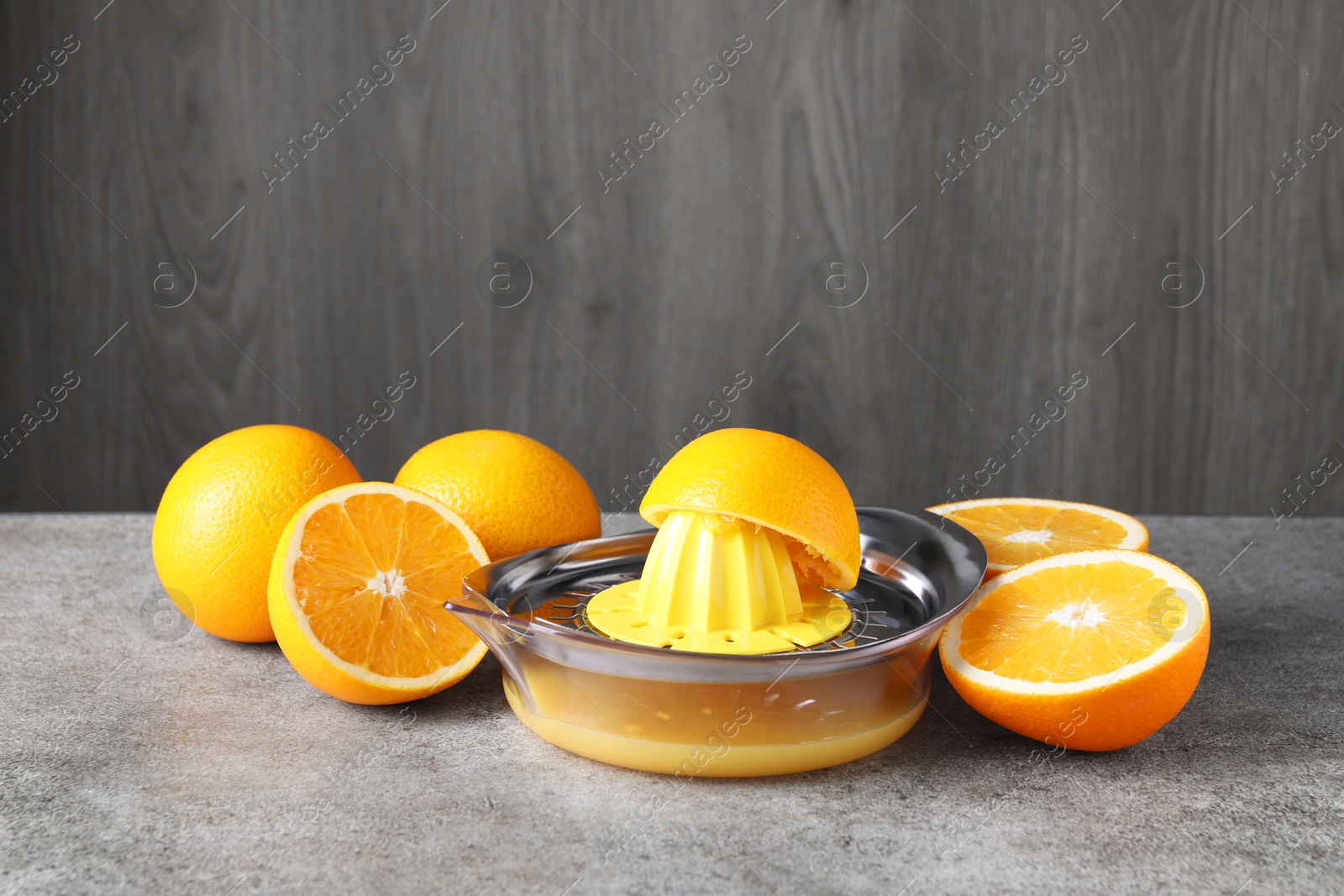 Photo of Metal juicer and oranges on grey table