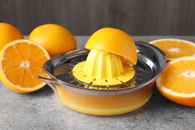 Photo of Metal juicer and oranges on grey table, closeup