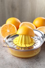 Photo of Metal juicer and oranges on grey table, closeup