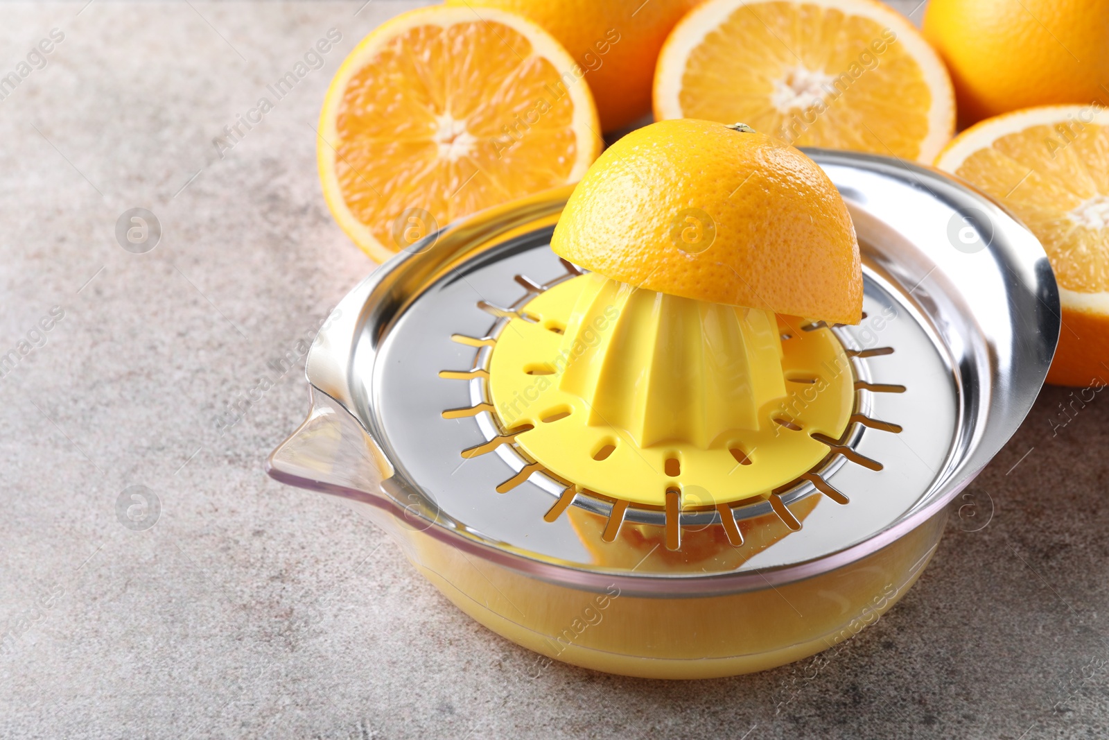 Photo of Metal juicer and oranges on grey table, closeup