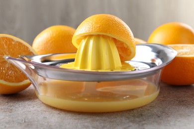 Photo of Metal juicer and oranges on grey table, closeup