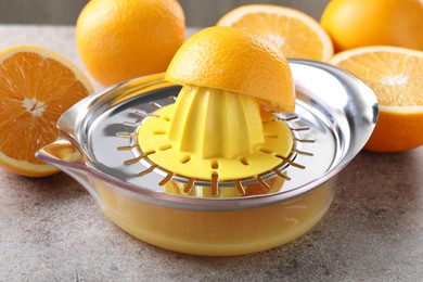 Photo of Metal juicer and oranges on grey table, closeup