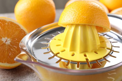 Photo of Metal juicer and oranges on table, closeup