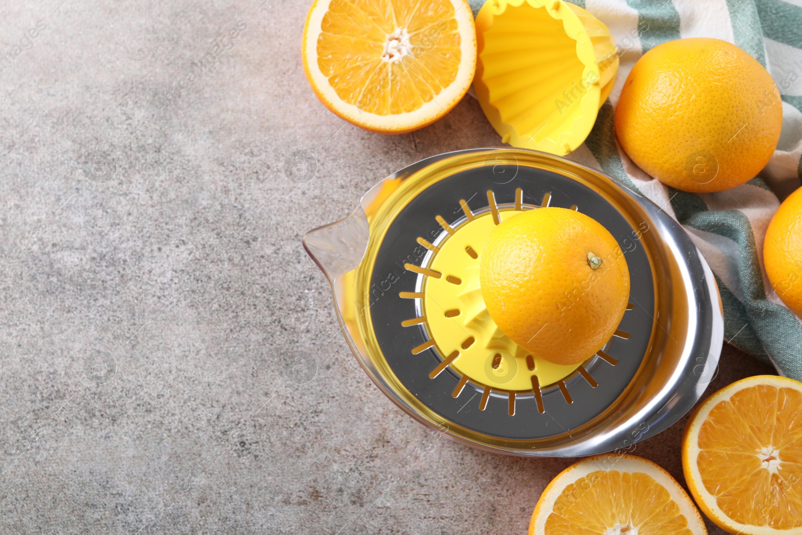 Photo of Metal juicer and oranges on grey table, top view. Space for text