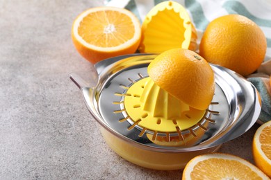 Photo of Metal juicer and oranges on grey table, closeup