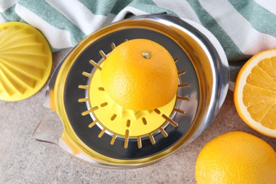 Photo of Metal juicer and oranges on grey table, top view