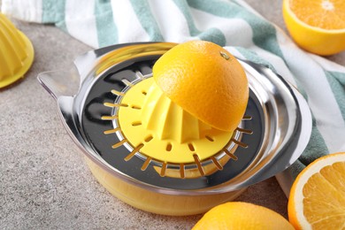 Photo of Metal juicer and oranges on grey table, closeup