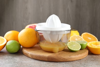 Photo of Plastic juicer and different citrus fruits on grey table