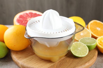 Photo of Plastic juicer and different citrus fruits on table, closeup