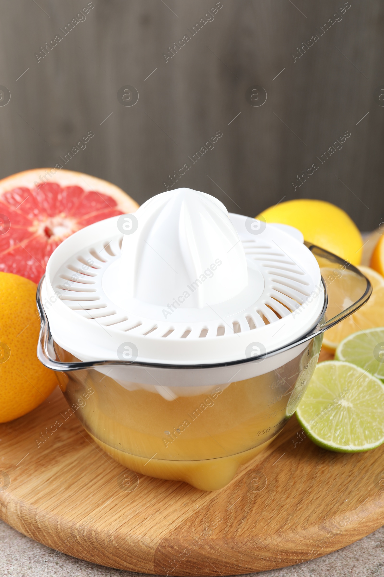 Photo of Plastic juicer and different citrus fruits on table, closeup