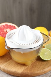 Photo of Plastic juicer and different citrus fruits on table, closeup