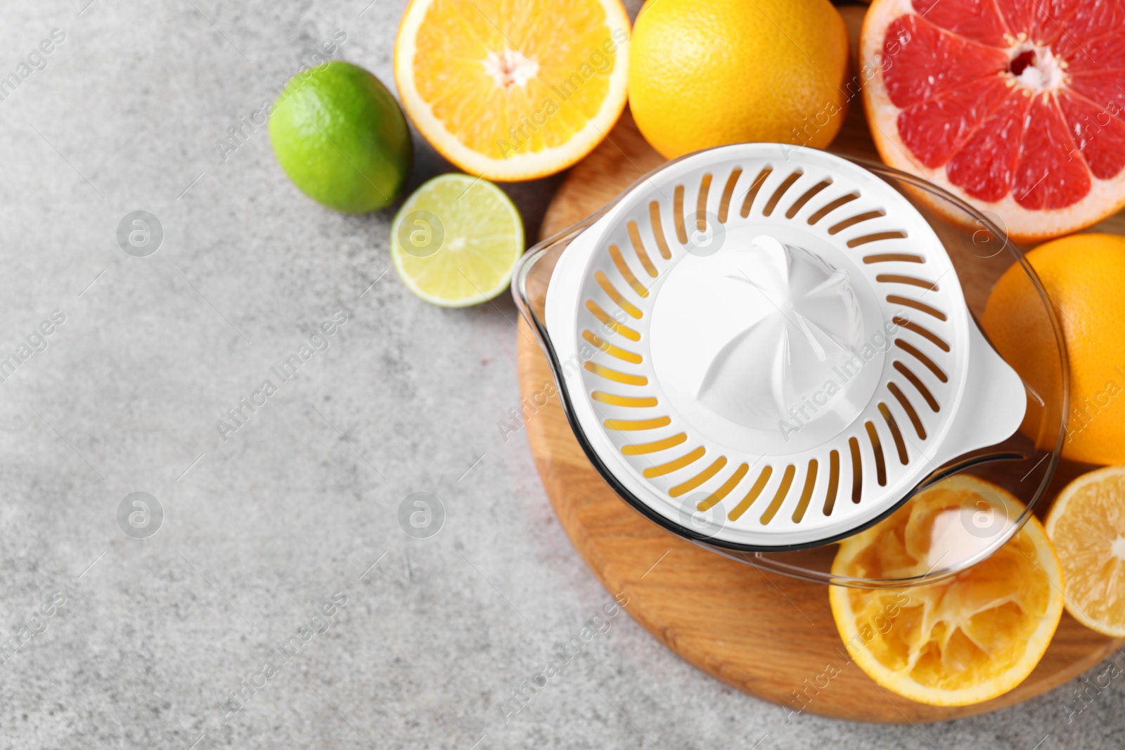 Photo of Plastic juicer and different citrus fruits on grey table, top view. Space for text