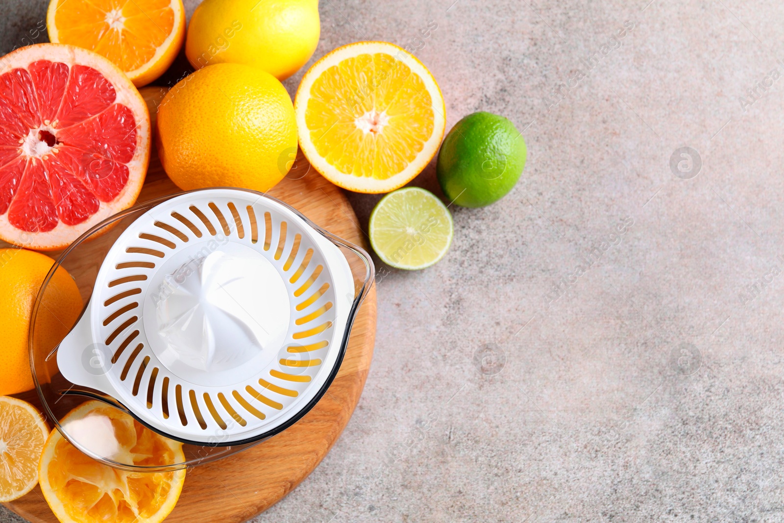 Photo of Plastic juicer and different citrus fruits on grey table, top view. Space for text