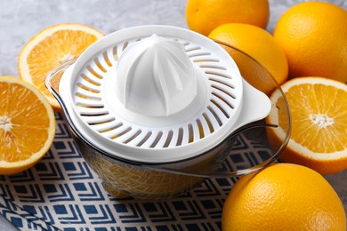 Photo of Plastic juicer and oranges on table, closeup