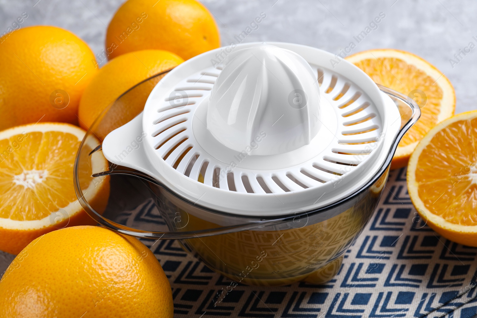 Photo of Plastic juicer and oranges on table, closeup