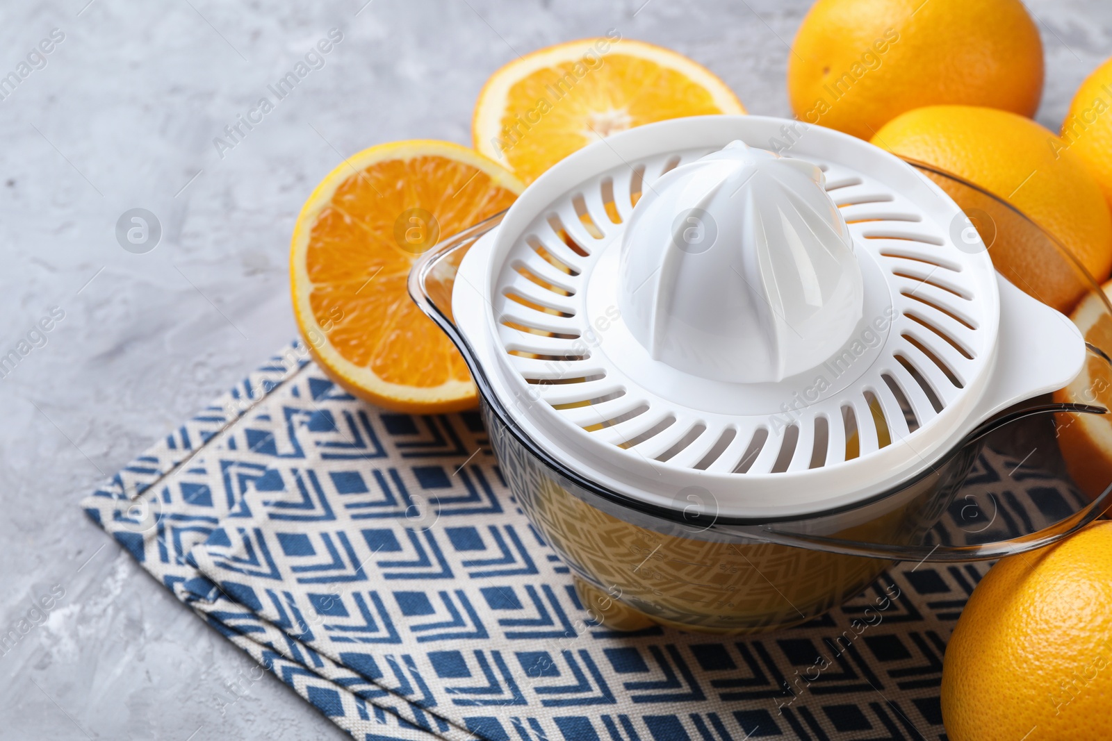 Photo of Plastic juicer and oranges on grey table, closeup