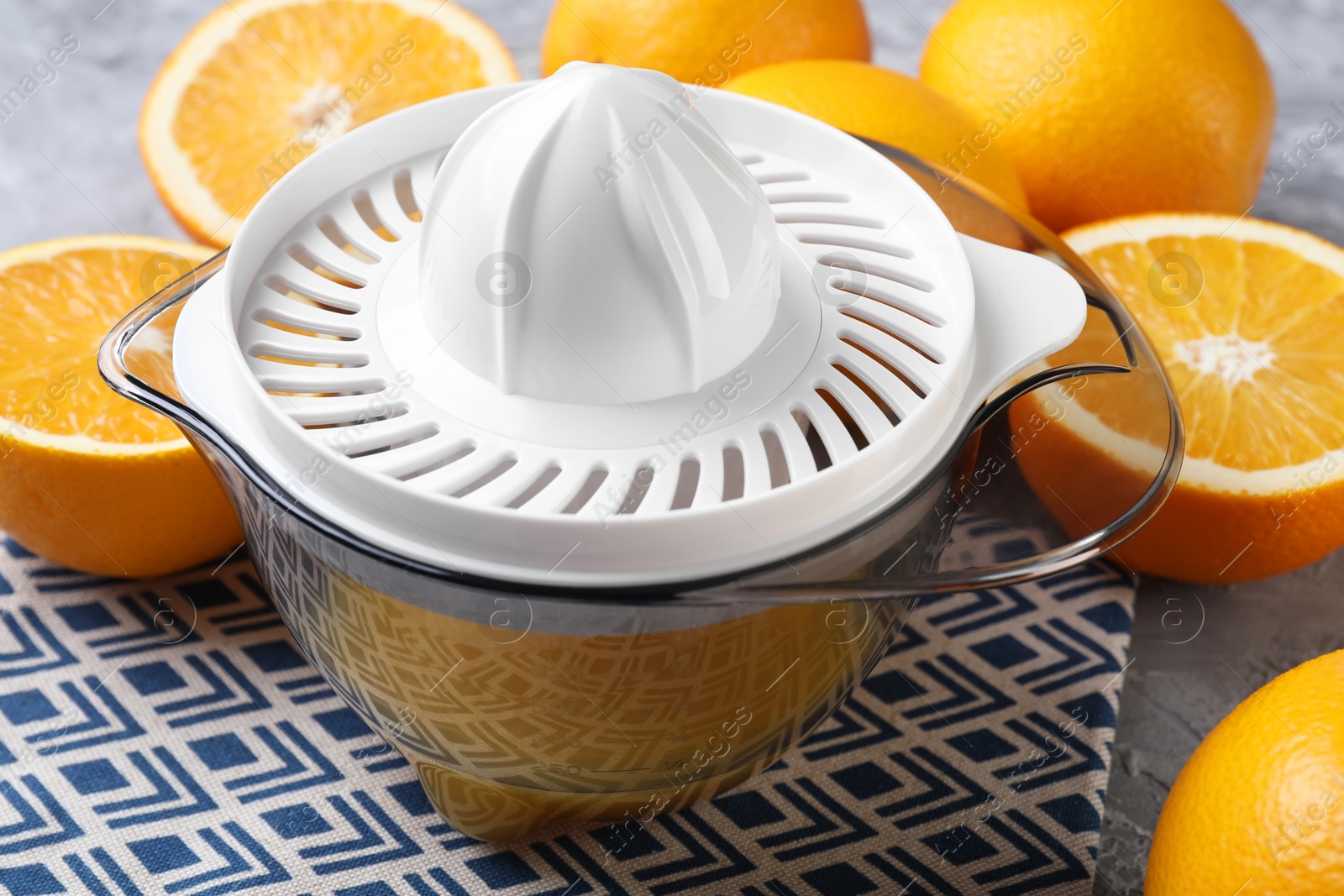 Photo of Plastic juicer and oranges on table, closeup