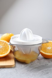 Photo of Plastic juicer and oranges on grey table