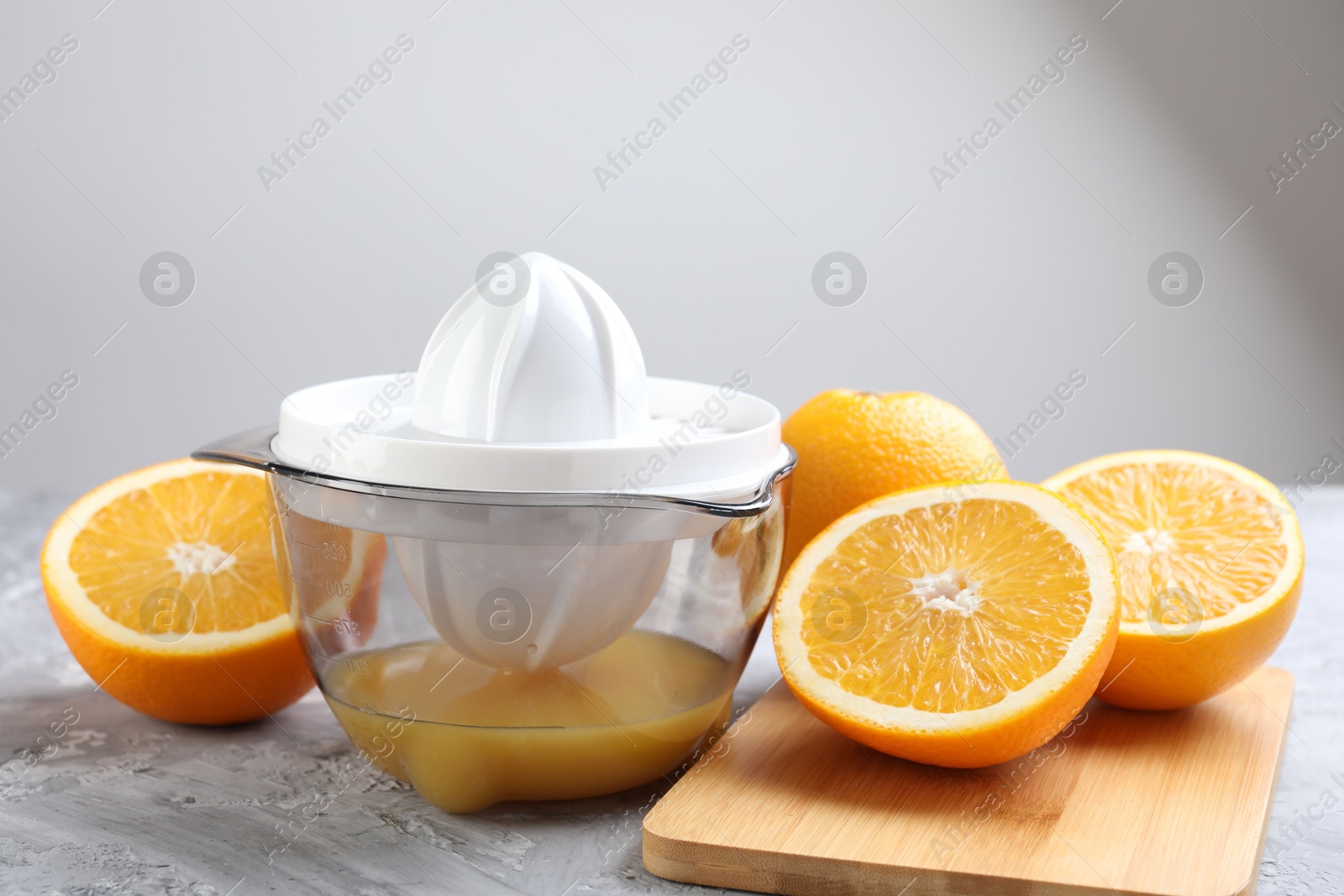 Photo of Plastic juicer and oranges on grey table