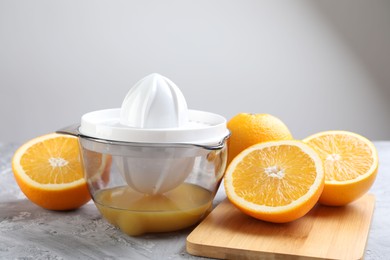 Photo of Plastic juicer and oranges on grey table