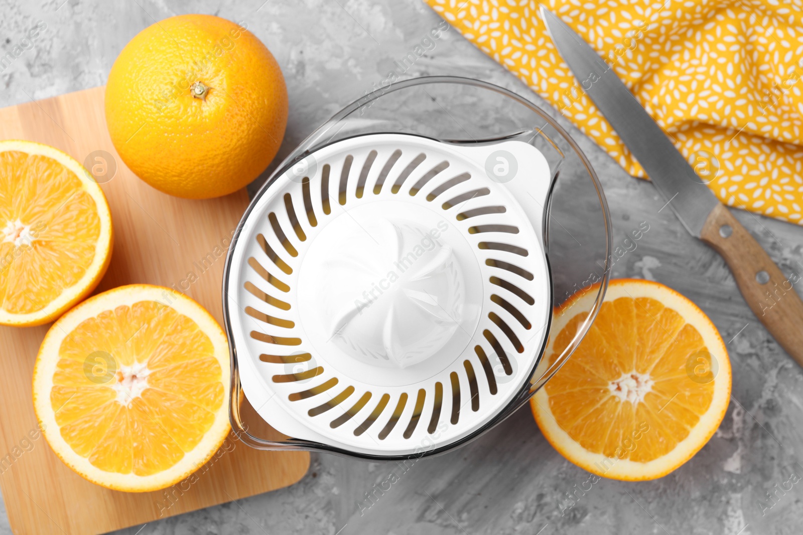 Photo of Plastic juicer, oranges and knife on grey table, top view