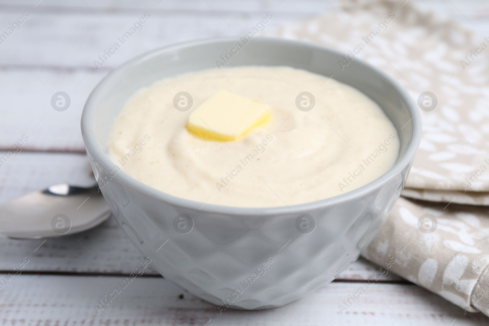 Photo of Tasty cooked semolina porridge with butter on white wooden table, closeup