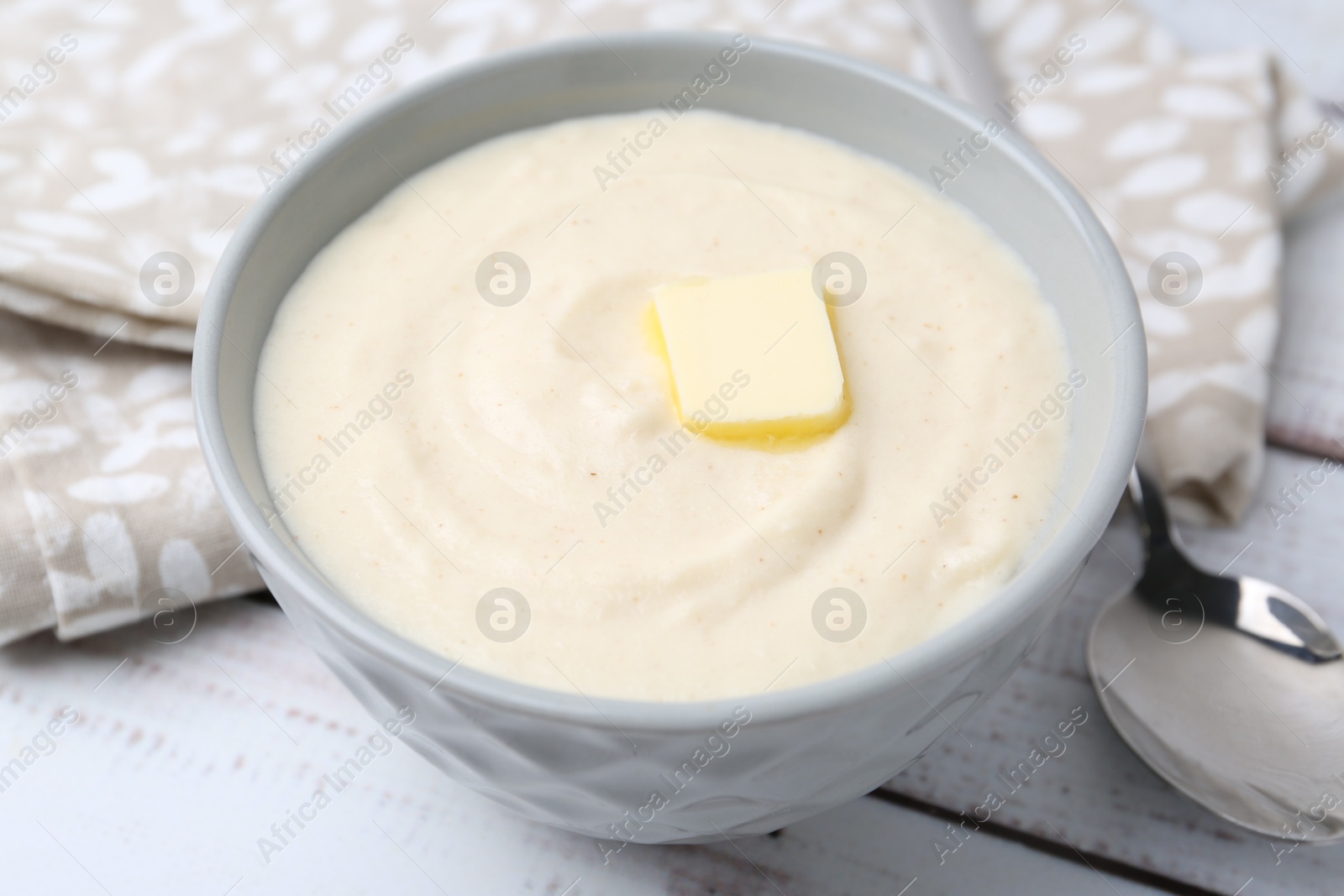 Photo of Tasty cooked semolina porridge with butter on white wooden table, closeup