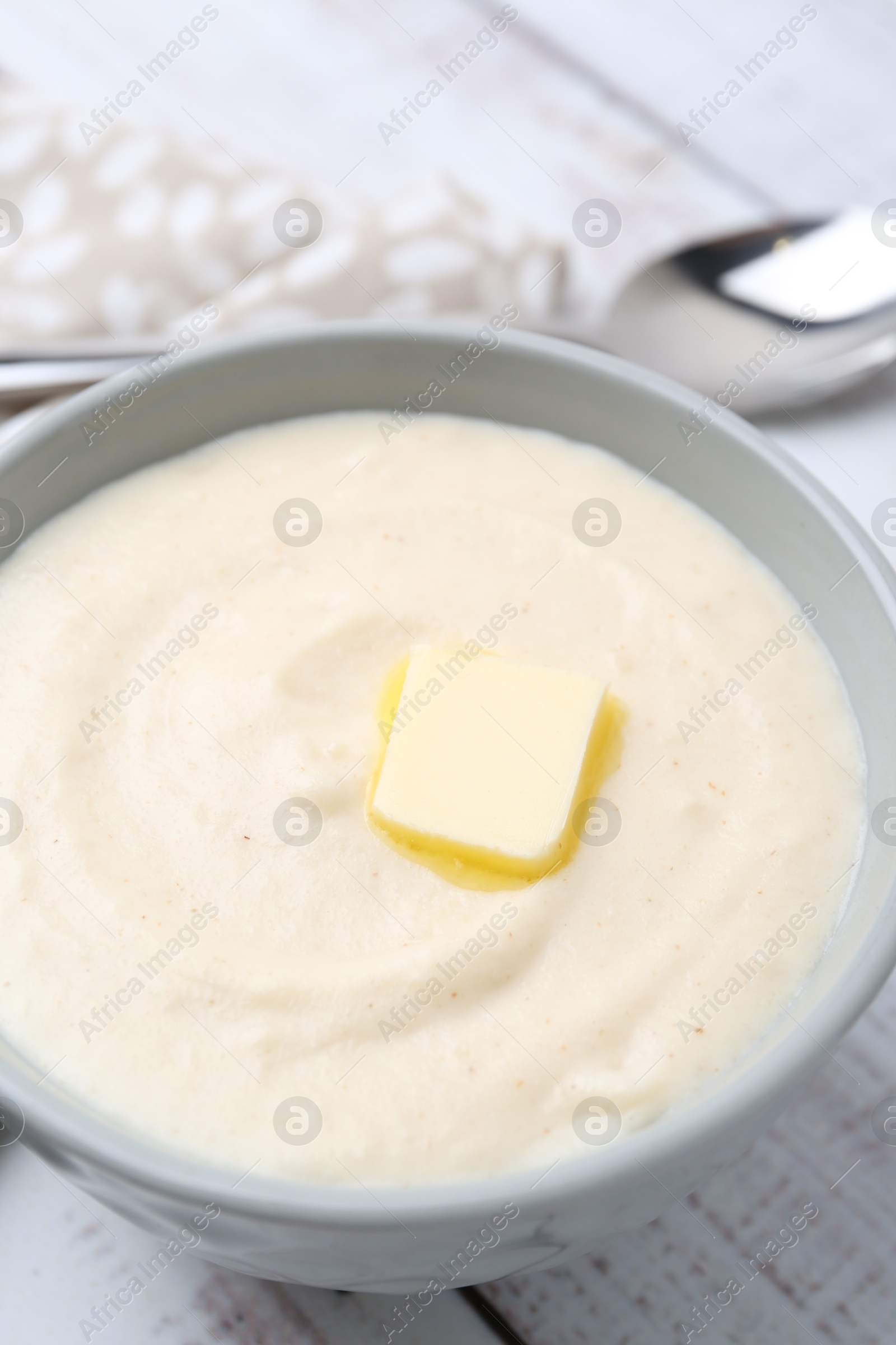 Photo of Tasty cooked semolina porridge with butter on white wooden table, closeup