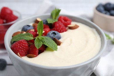 Tasty cooked semolina porridge with almonds, berries and mint on table, closeup