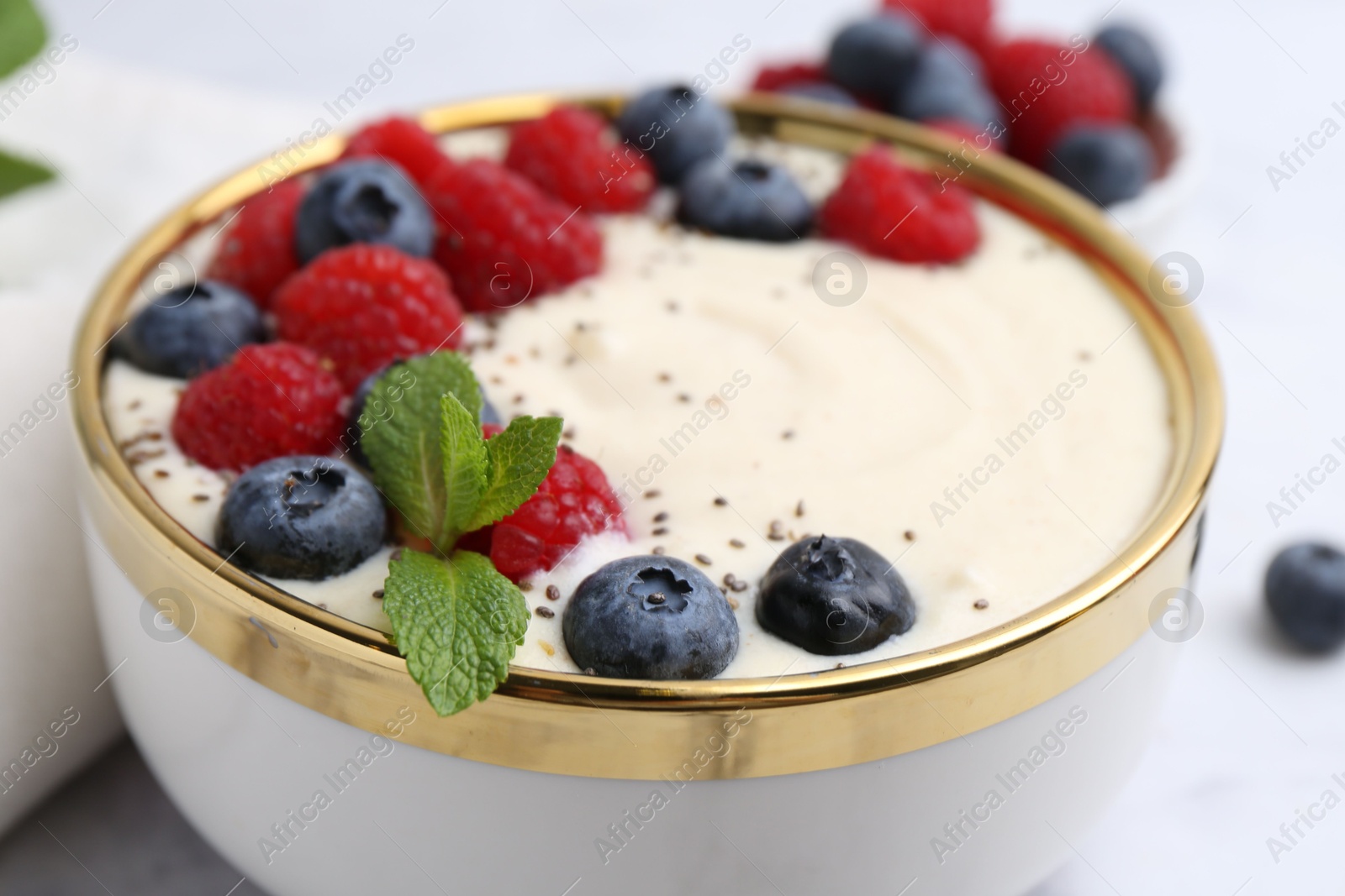 Photo of Tasty cooked semolina porridge with berries and mint on table, closeup